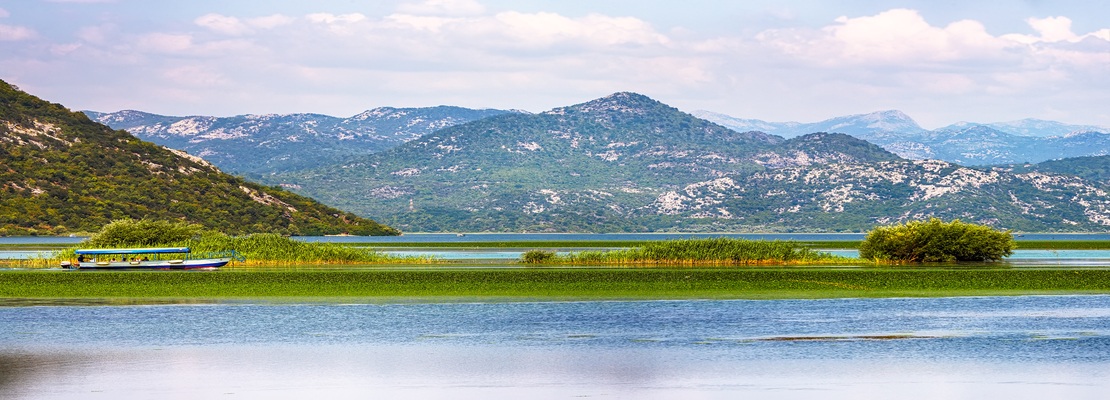 Panoramic view of Lake Skadar surrounded by green mountains