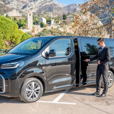 Professional chauffeur opening the door of a Toyota Proace Verso in Stari Bar, Bar, Montenegro, operated by LAZEX TRANSFER