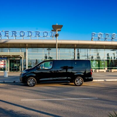 Toyota Proace Verso passenger van by LAZEX TRANSFER parked in front of Podgorica Airport, Montenegro.